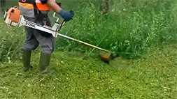 Radnik kosi travu na vikednici | Preduzimač Video prikaz košenja trave motornim trimerom | Preduzimač